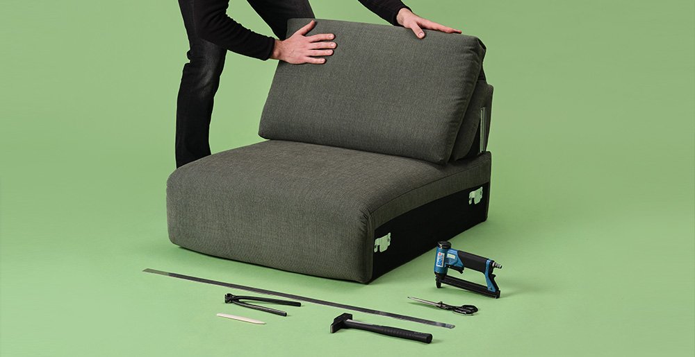 Ein Sofa-Experte verarbeitet ein Sofasitz mit dem benötigten Werkzeug.