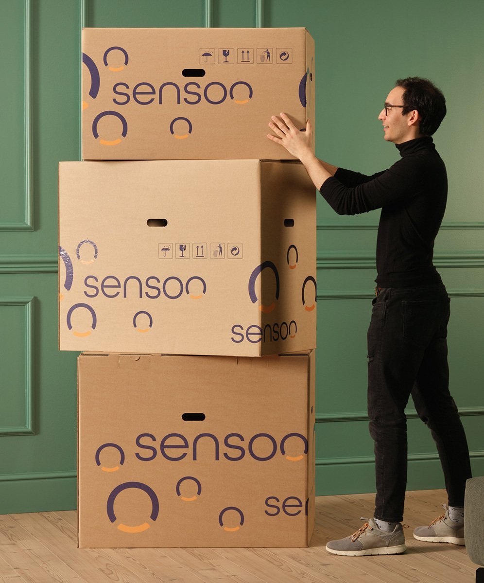Un jeune homme se tient à côté de l'emballage de Sensoo. On voit trois boîtes.